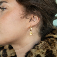 Close-up of a person wearing a gold hoop earring with a leopard print fur garment - seolgold