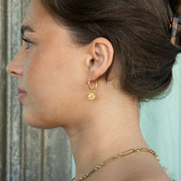 Close-up of a woman wearing gold hoop earrings and a necklace against a blurred background - seolgold