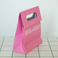 Pink paper bag with 'SEOL+GOLD' text on a white background - seolgold