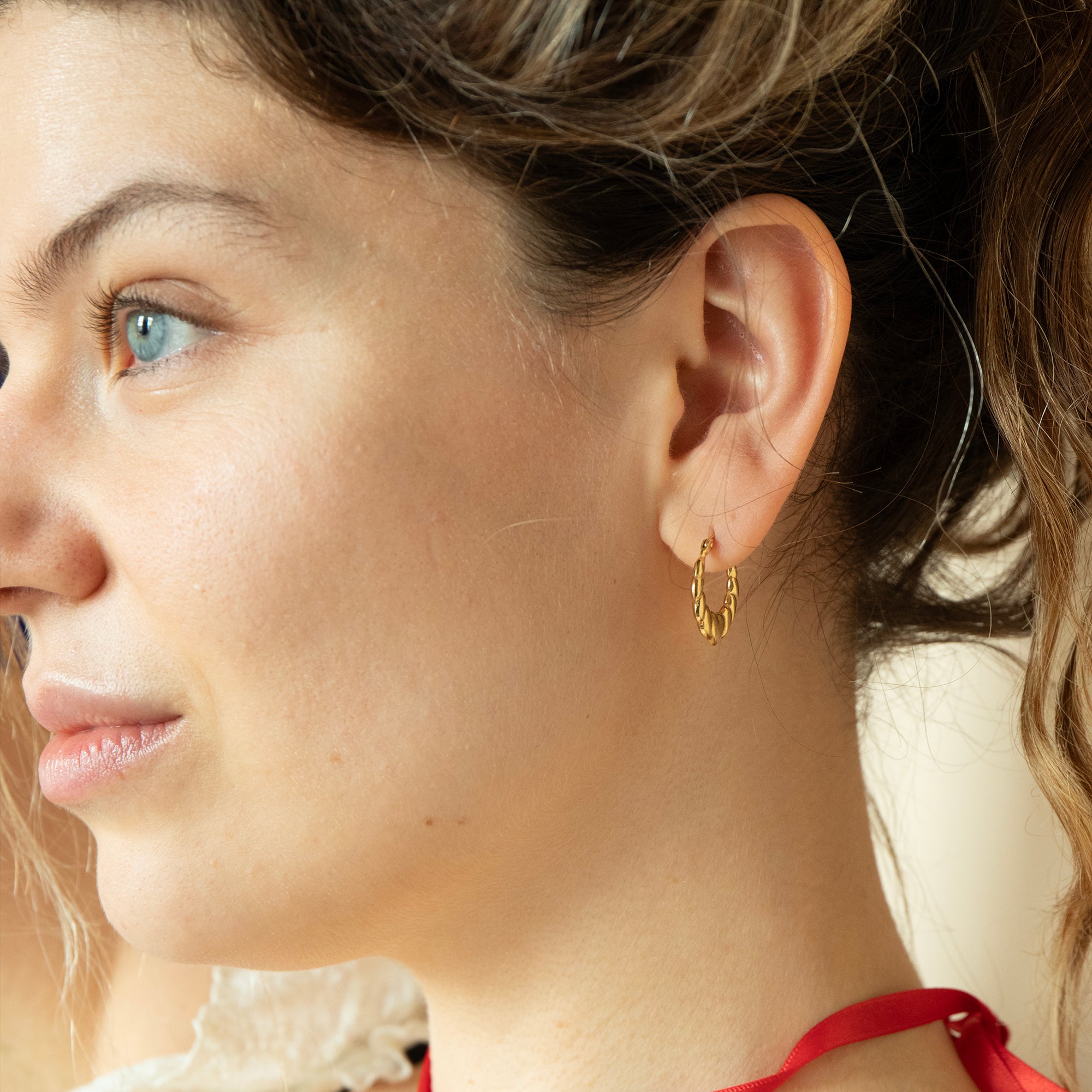 Close-up of a woman wearing a gold hoop earring with a blurred background - SEOLGOLD
