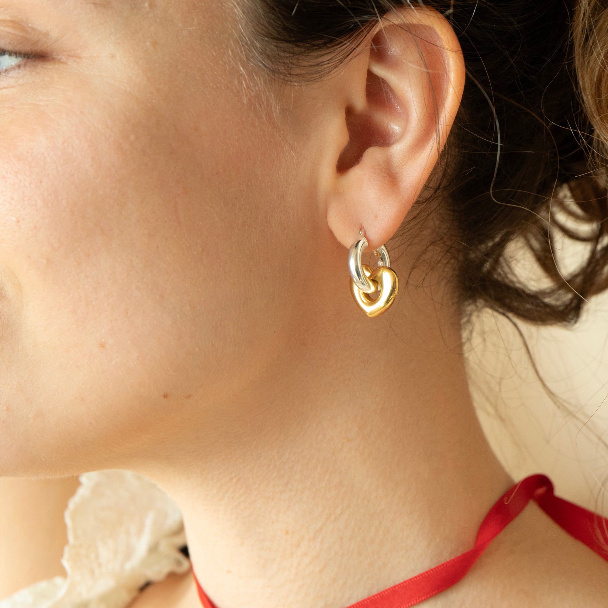 Close-up of a person wearing gold hoop earrings with a blurred background - seolgold