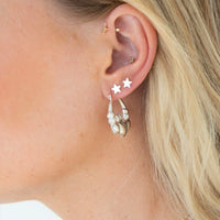 Close-up of an ear with multiple earrings including star-shaped studs and hoop earrings - seolgold