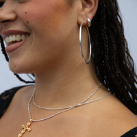 Close-up of a woman wearing silver hoop earrings and necklaces - solid gold hoop - seolgold