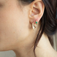 Close-up of an ear wearing gold hoop earrings with green gemstones - seolgold