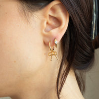 Close-up of a person wearing gold bow-shaped earrings - seolgold