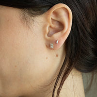 Close-up of an ear wearing a opal stud earring with hair partially covering the face - seolgold