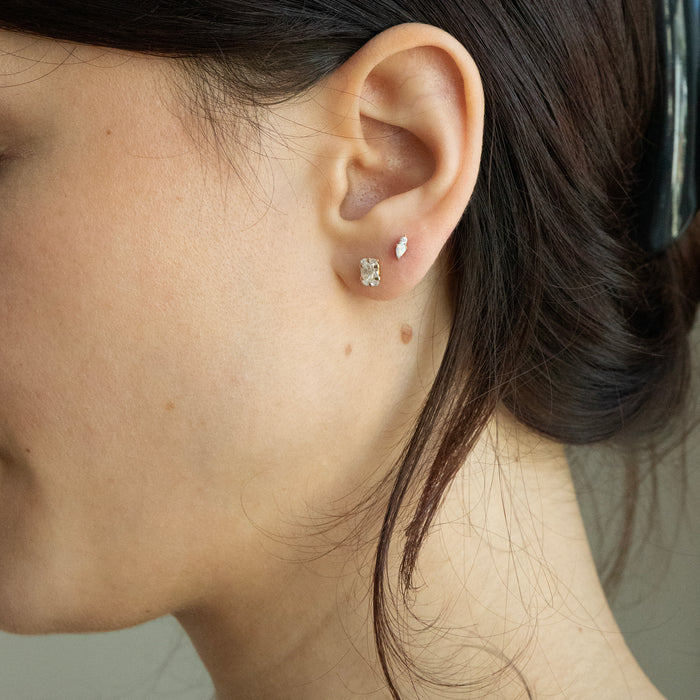 Close-up of a person wearing diamond stud earrings with a neutral background - seolgold