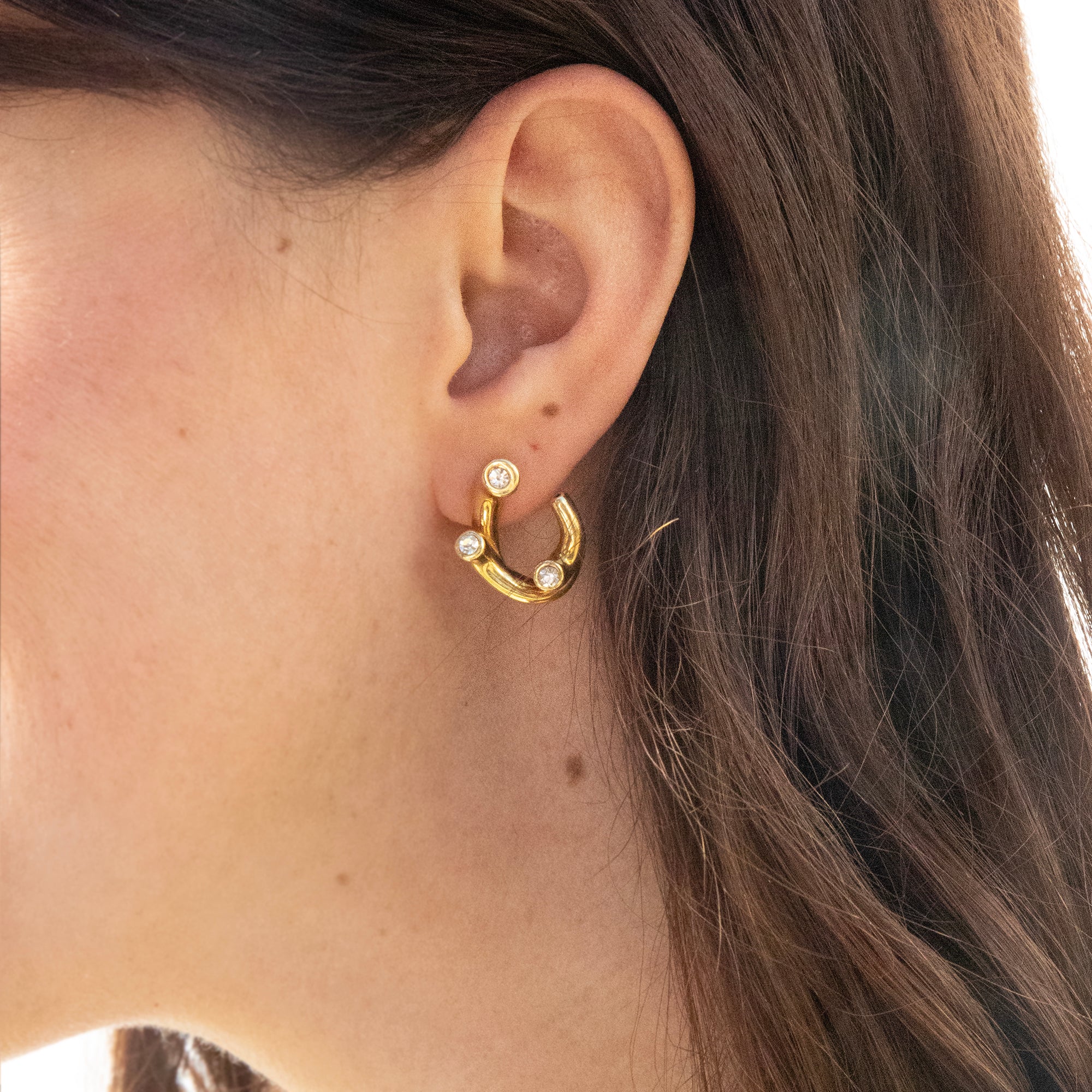 Gold hoop earring with small diamonds worn by a person with long brown hair - seolgold