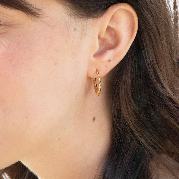 Close-up of an ear wearing a gold hoop earring with hair partially covering the face - seolgold