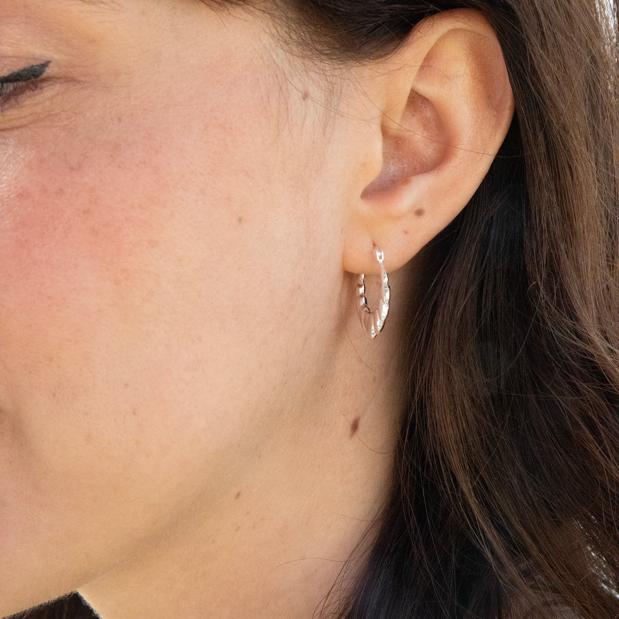 Close-up of an ear wearing a silver earring with a blurred background - seolgold