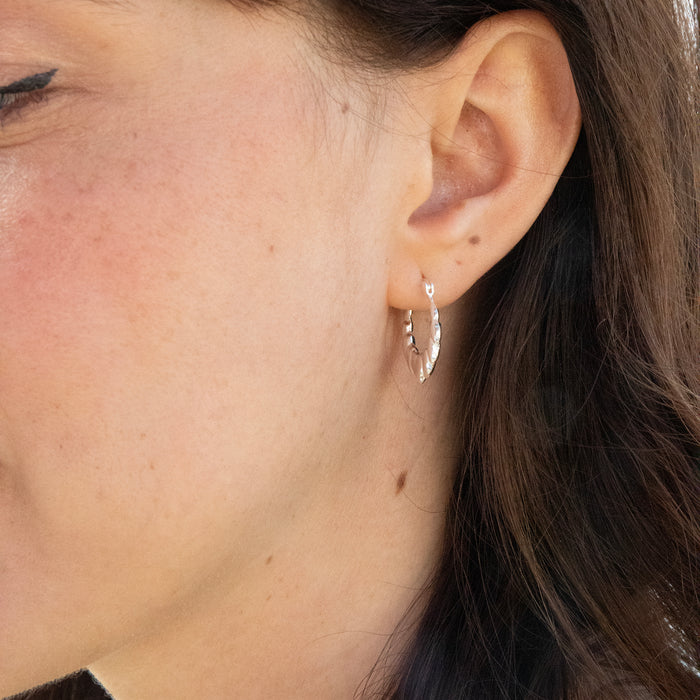 Close-up of an ear wearing a silver earring with a blurred background - seolgold