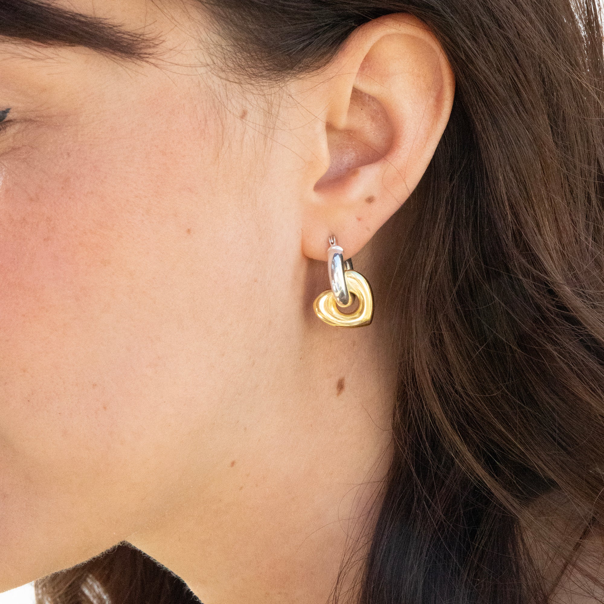 Close-up of a person wearing a gold heart-shaped earring - seolgold