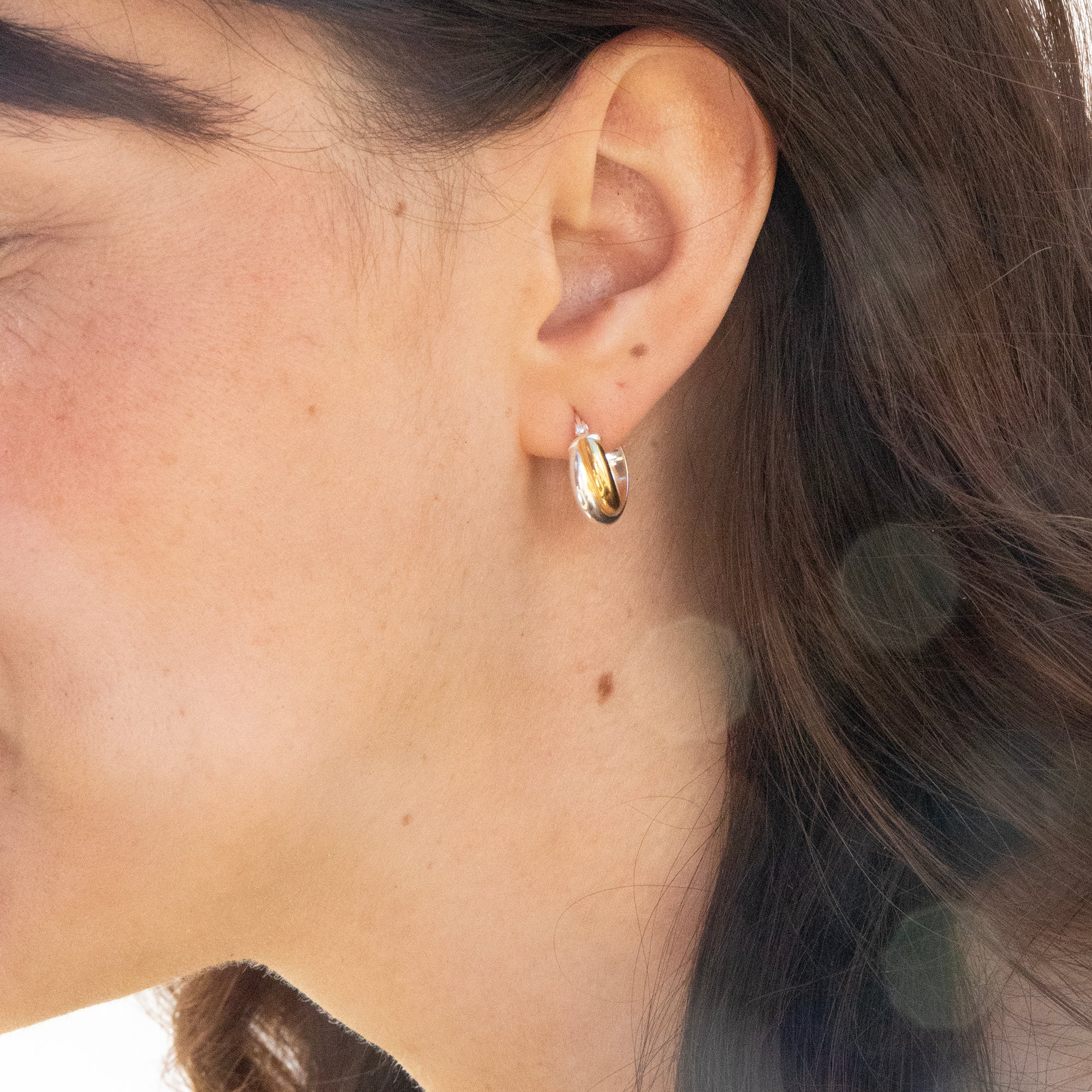 Close-up of an ear wearing a gold earring with hair partially obscuring the view - seolgold