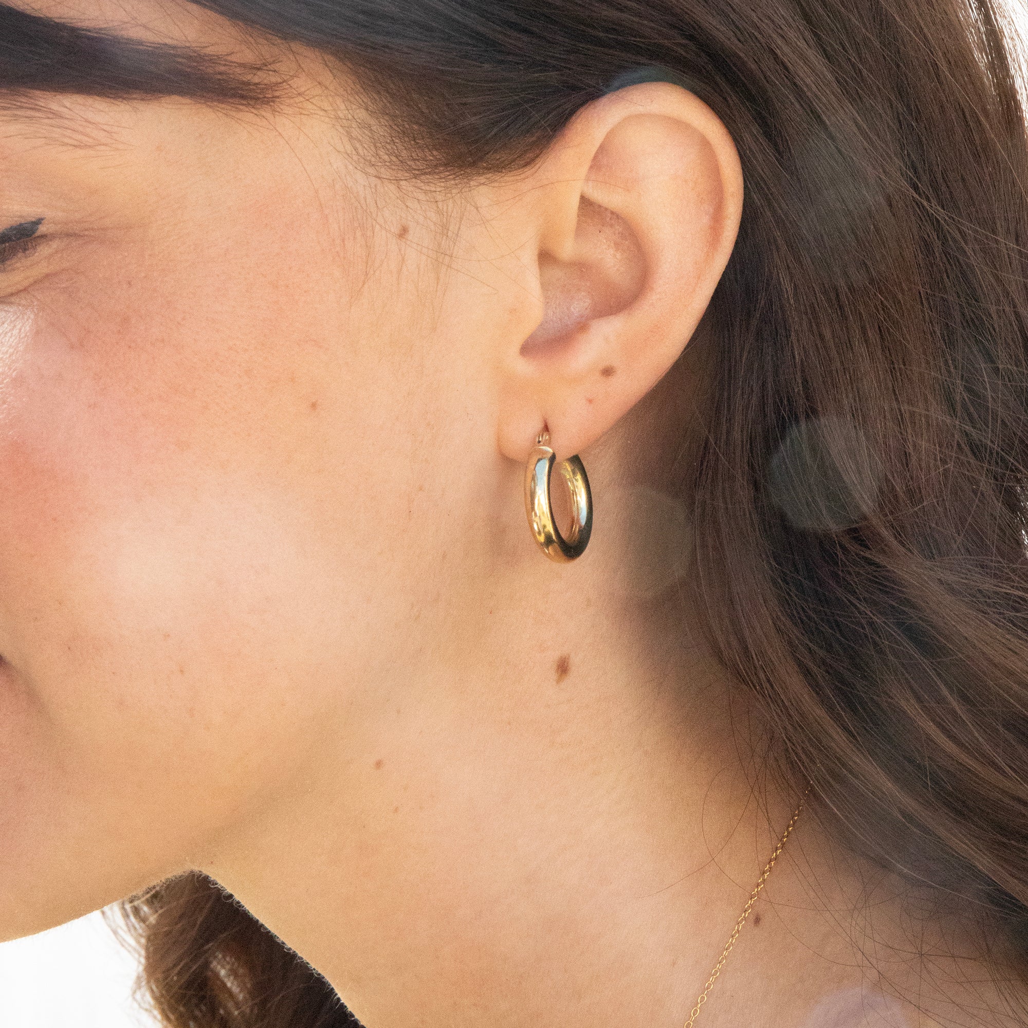 Close-up of a person wearing gold hoop earrings - seolgold