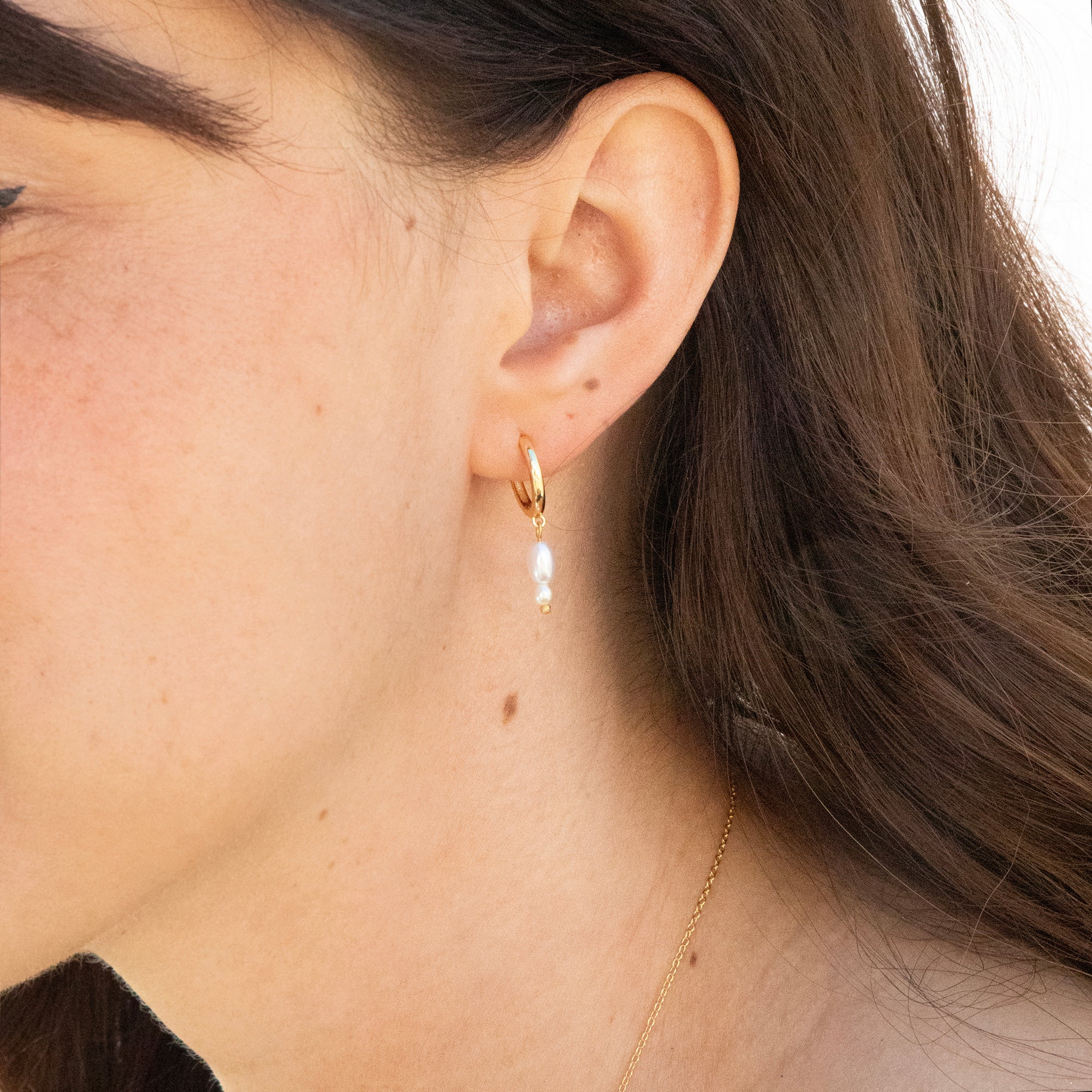 Close-up of a person wearing a gold hoop earring with a pearl accent - seolgold