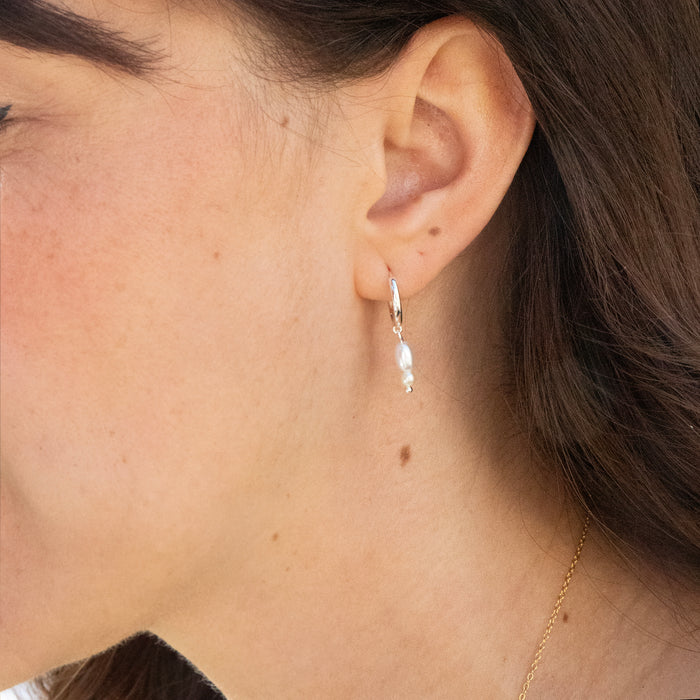 Close-up of an ear wearing a pearl earring with a blurred background - seolgold