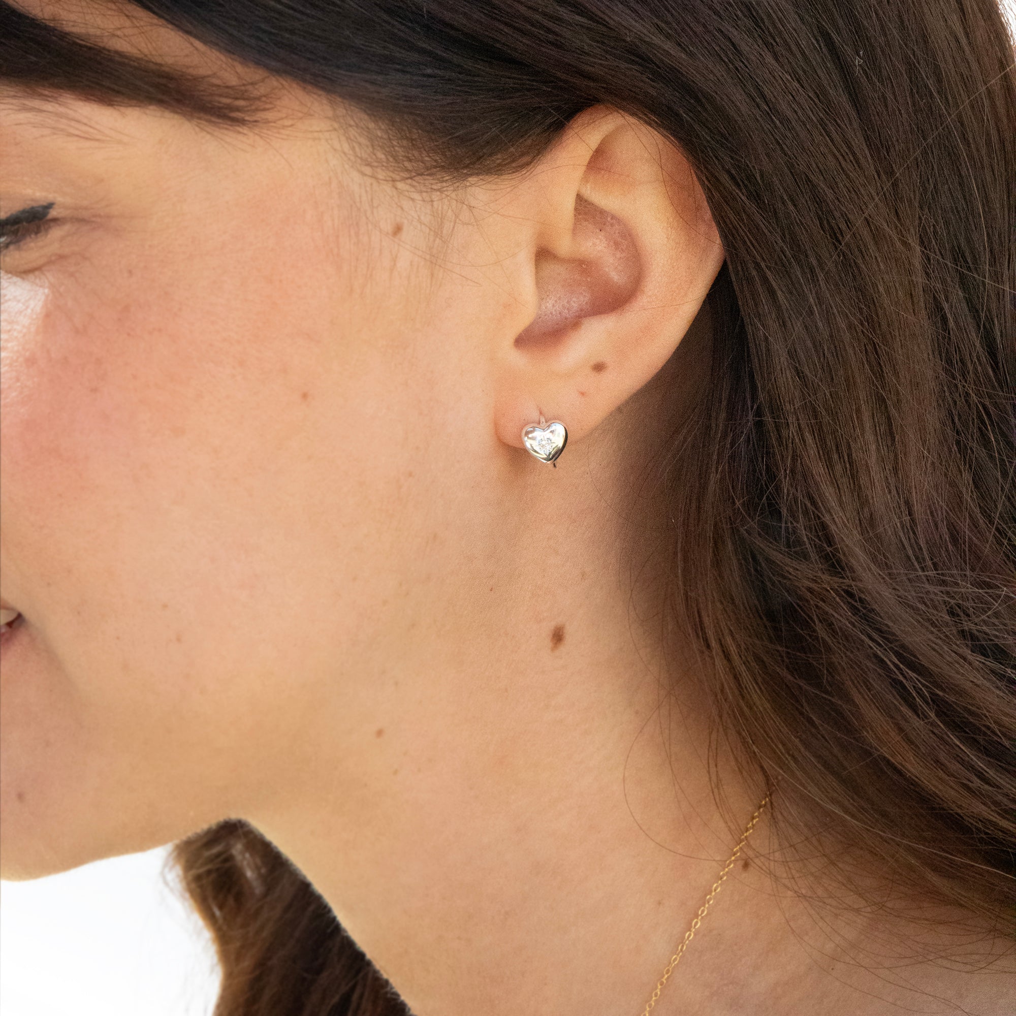 Close-up of a person wearing a tiny heart-shaped hoop earring - seolgold