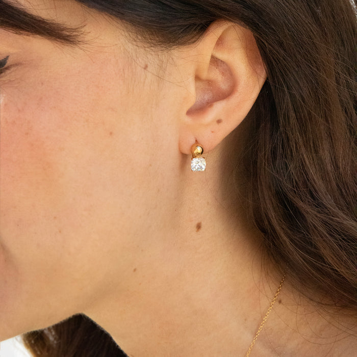 Close-up of an ear wearing gold earrings with a blurred background - seolgold