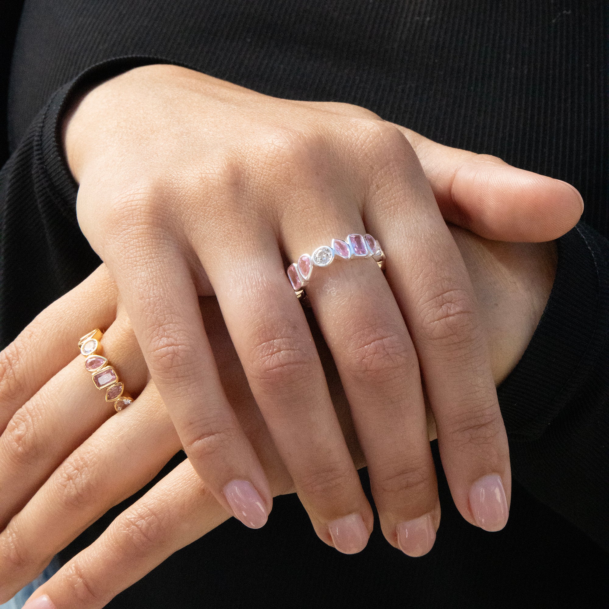 Close-up of a hand wearing multiple rings with gemstones on a black background - seolgold