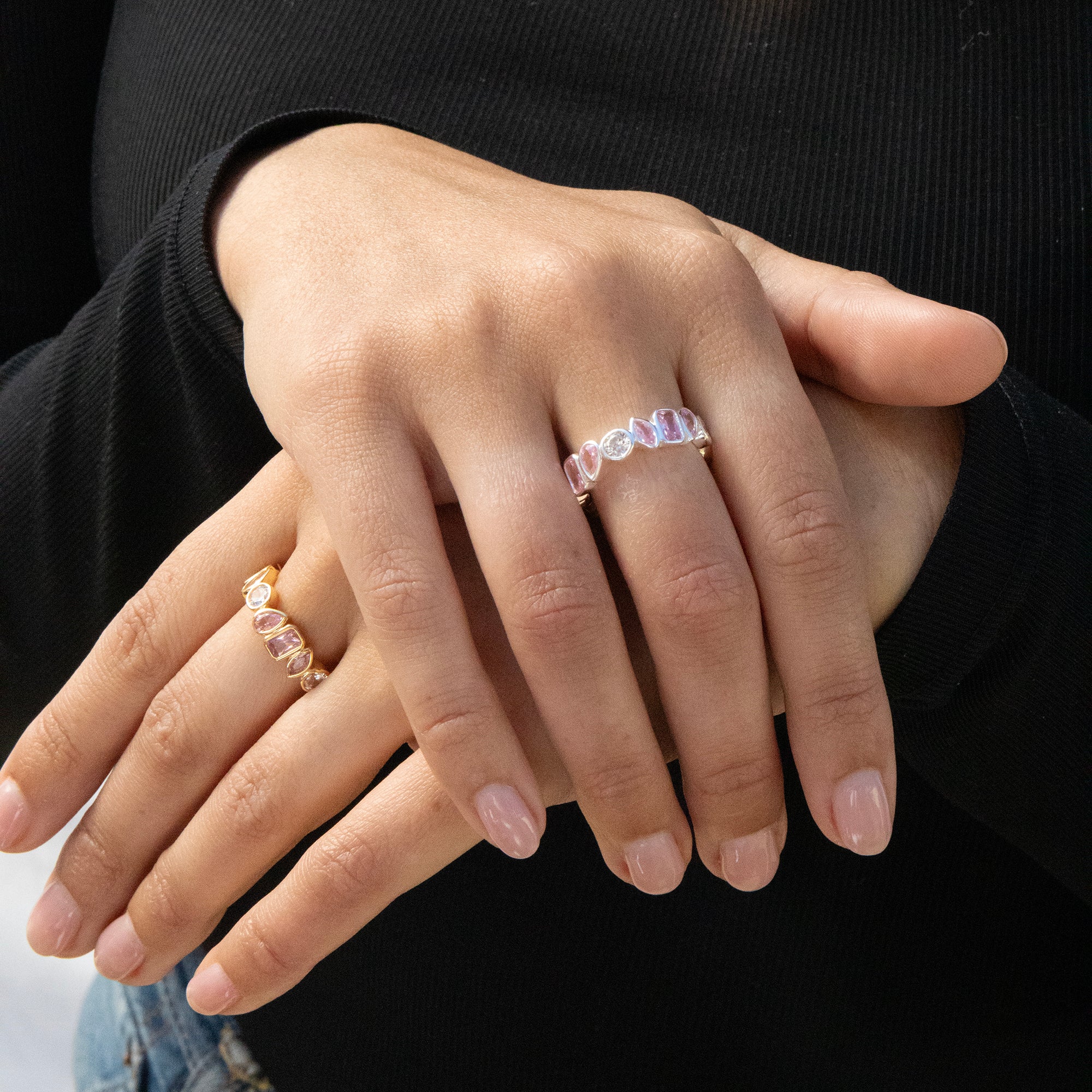 Close-up of hands wearing multiple rings with a black background - seolgold