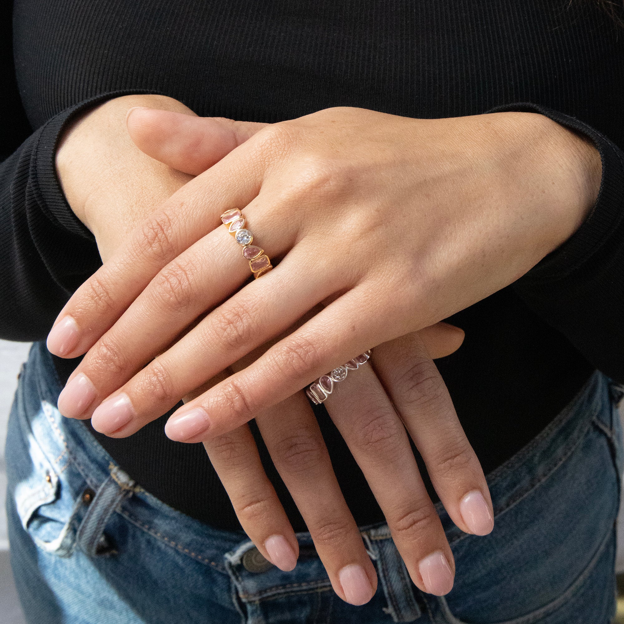 Close-up of hands with multiple rings on fingers against a neutral background - seolgold