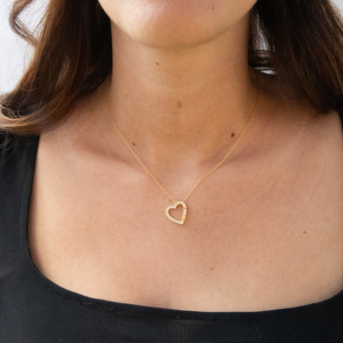 Gold heart-shaped necklace worn by a person with a plain background - seolgold