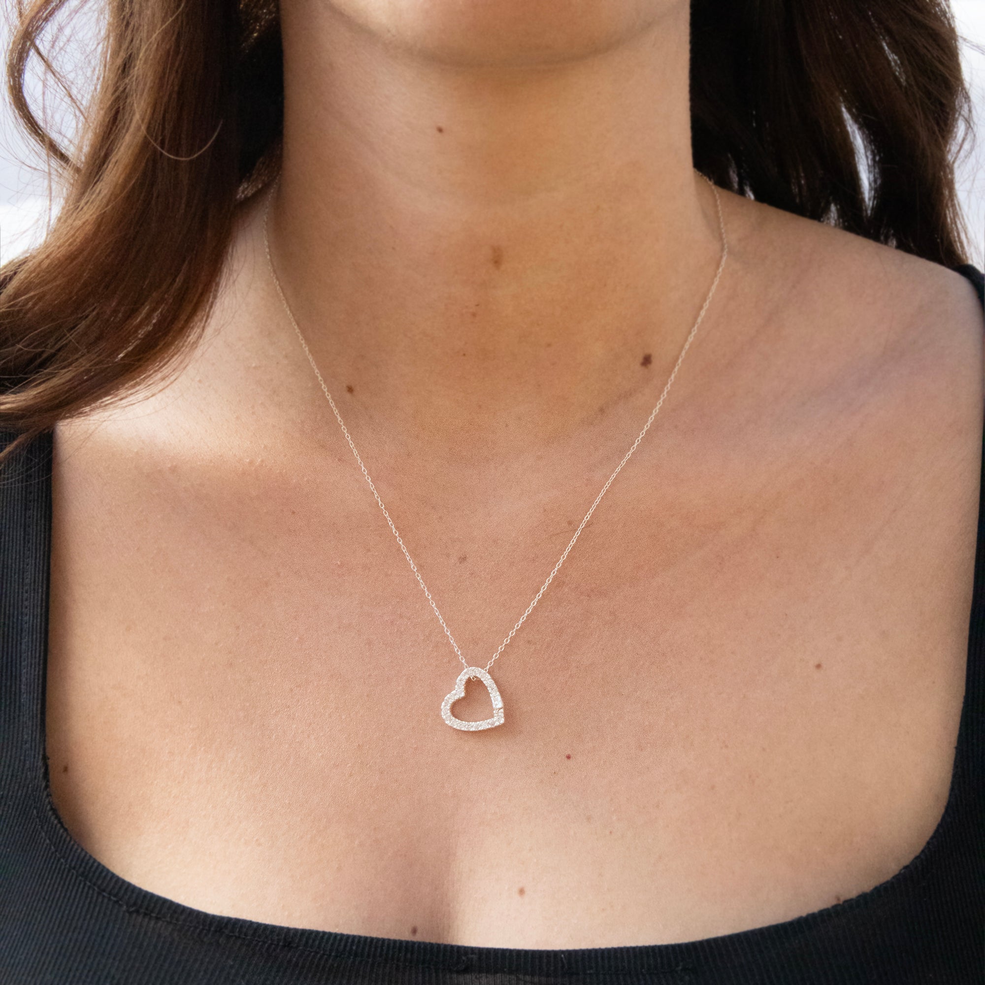 Heart-shaped silver necklace on a person wearing a black top - seolgold