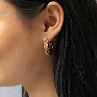 Close-up of an ear wearing a gold hoop earring with intricate design - seolgold