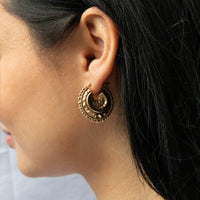 Close-up of a person wearing a gold hoop earring with intricate designs - seolgold