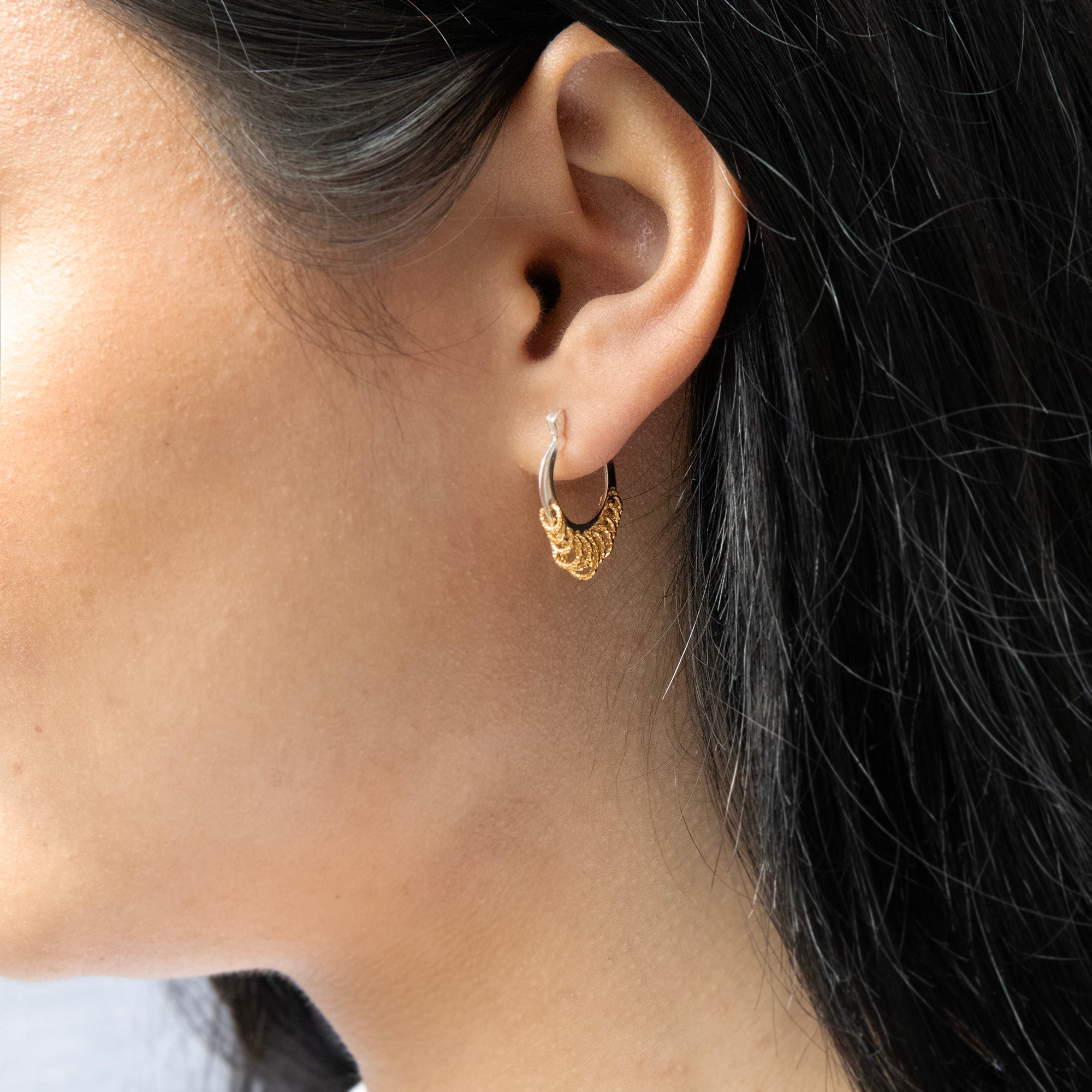 Close-up of a person wearing a gold hoop earring with a dark background - Mixed Metal Shaker Hoop Earrings - seolgold 