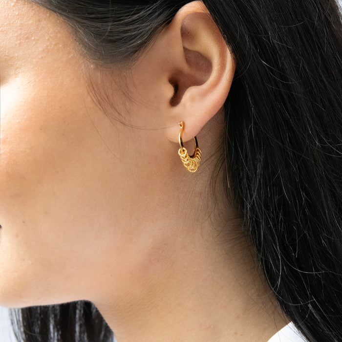 Close-up of a person wearing a gold hoop earring with intricate design - seolgold