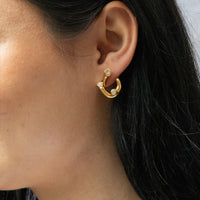 Gold hoop earrings with small diamonds worn by a person with dark hair - seolgold