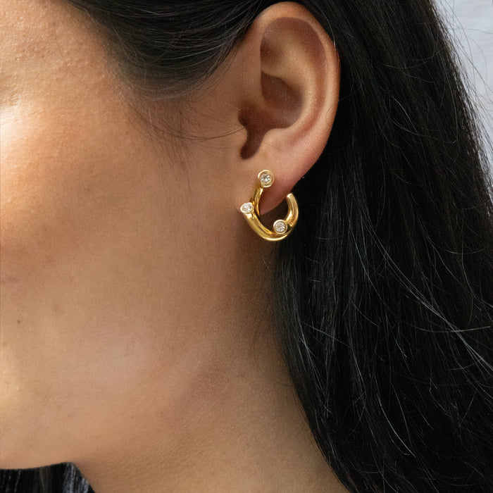 Gold hoop earrings with small diamonds worn by a person with dark hair - seolgold
