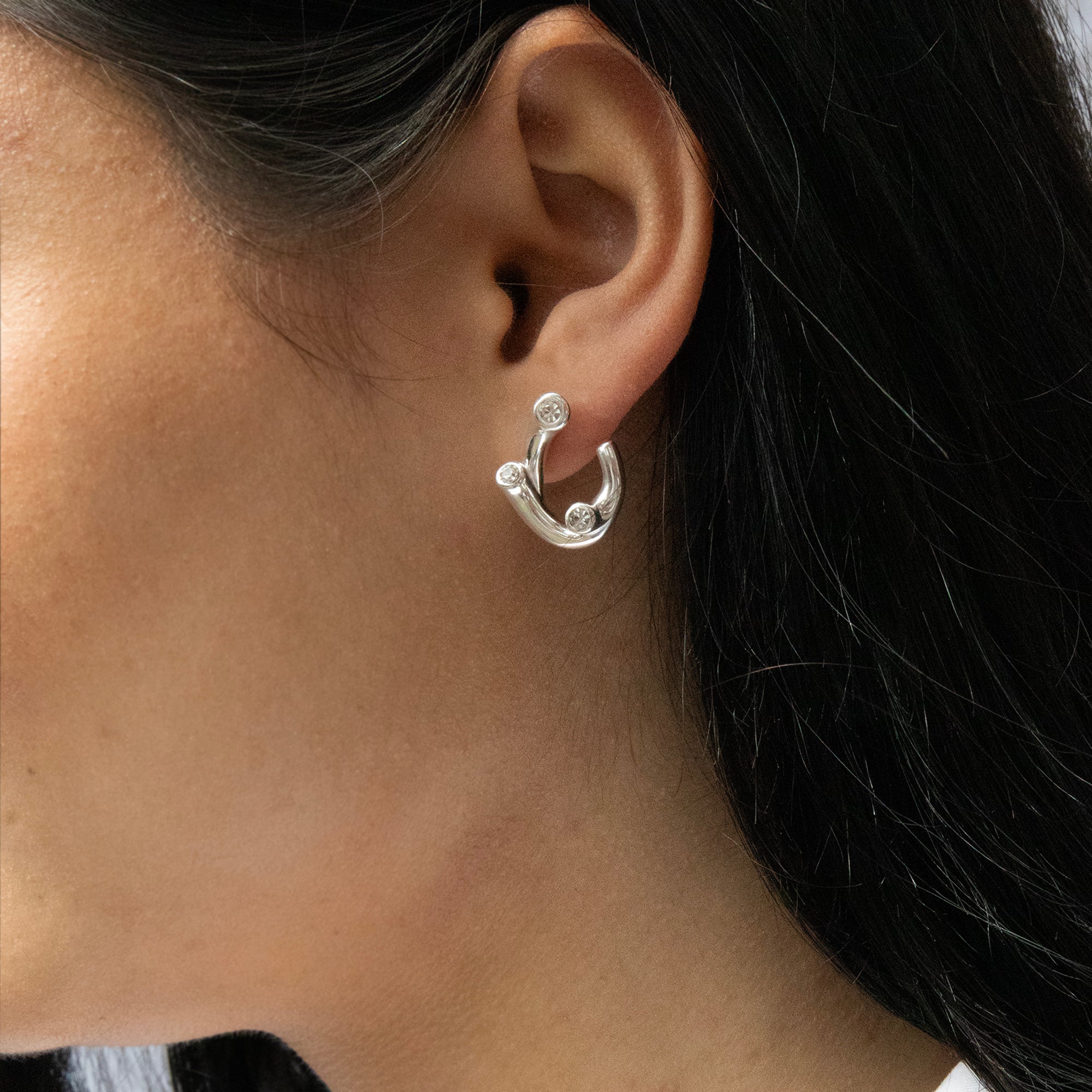 Silver hoop earring worn by a person with dark hair - seolgold