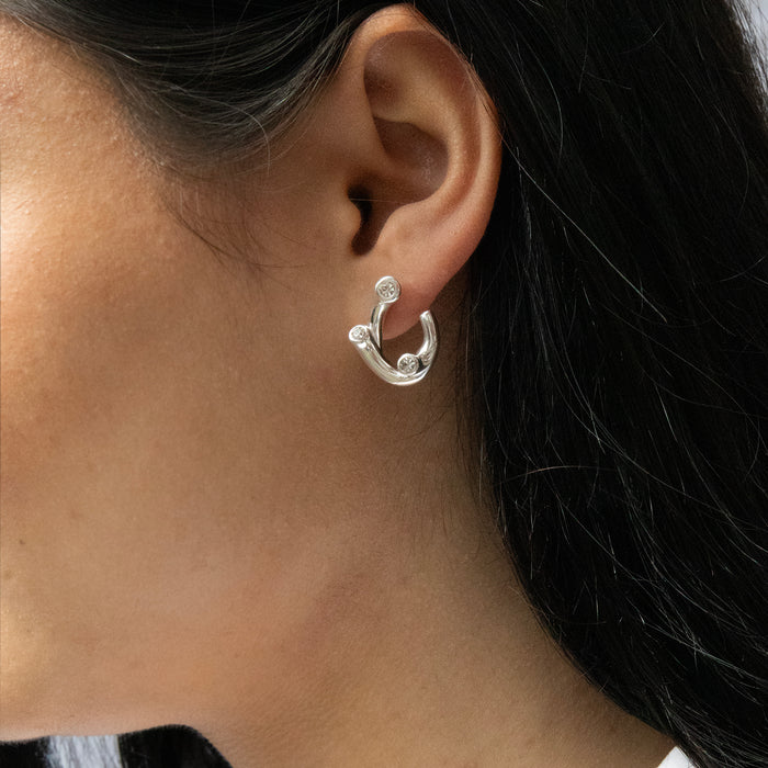 Silver hoop earring worn by a person with dark hair - seolgold
