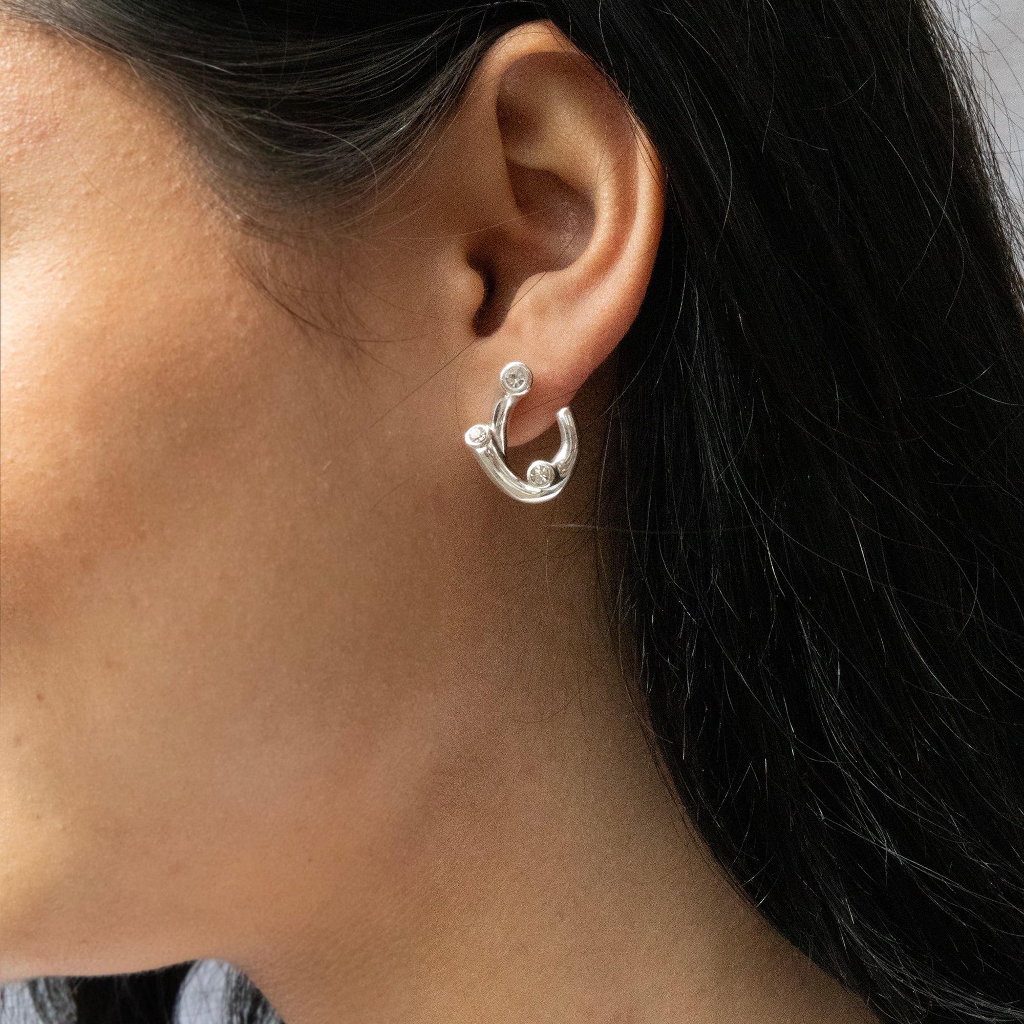Close-up of a person wearing a silver earring with dark hair - seolgold