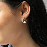 Close-up of a person wearing a silver earring with dark hair - seolgold