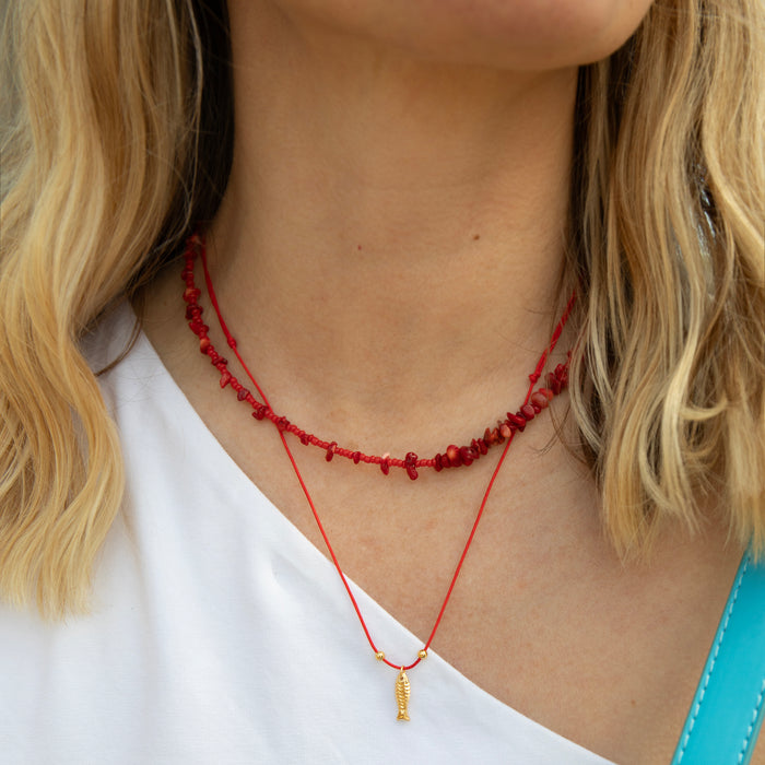 Close-up of a person wearing a red beaded necklace with a gold pendant - seolgold