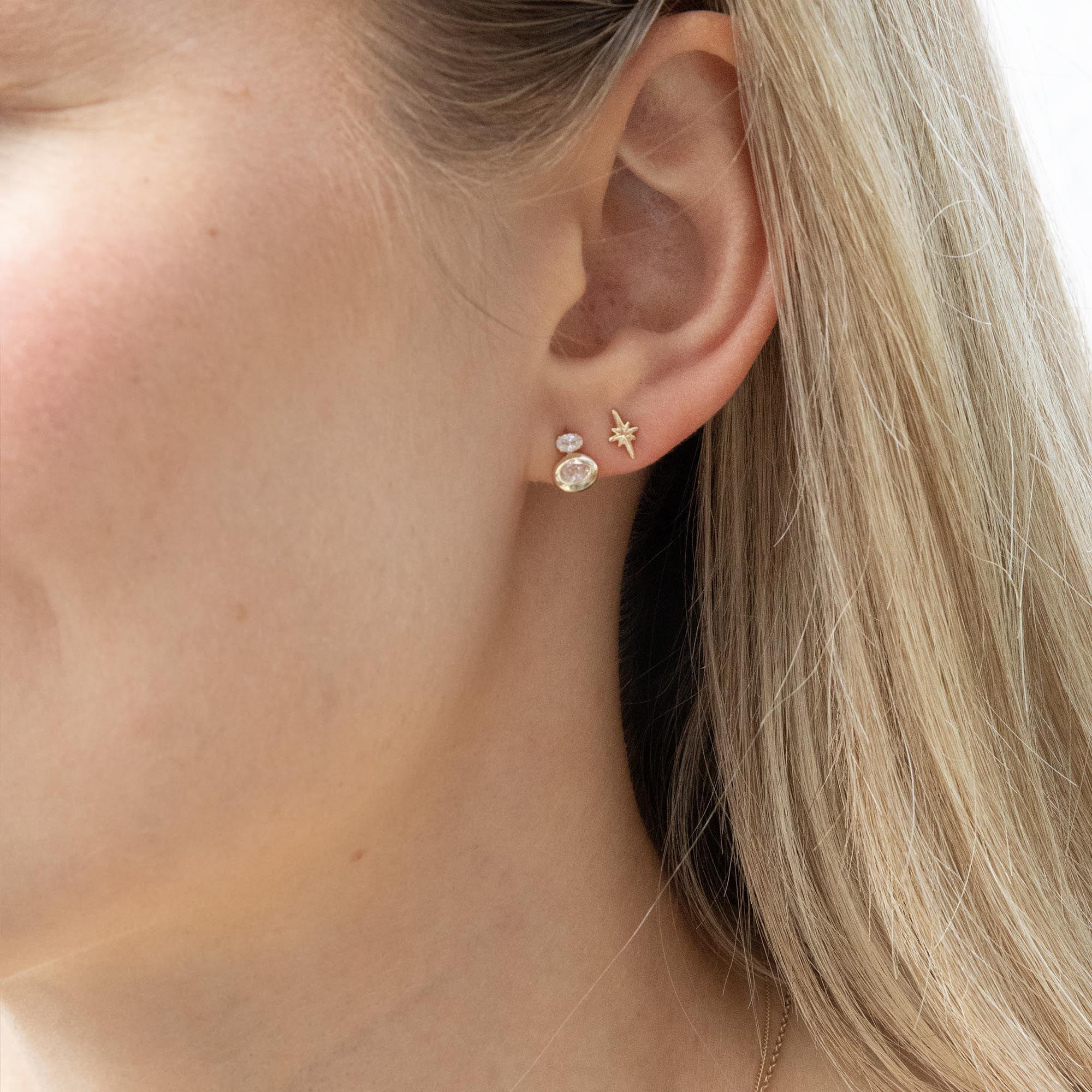 Close-up of an ear wearing gold earrings with a neutral background - seolgold