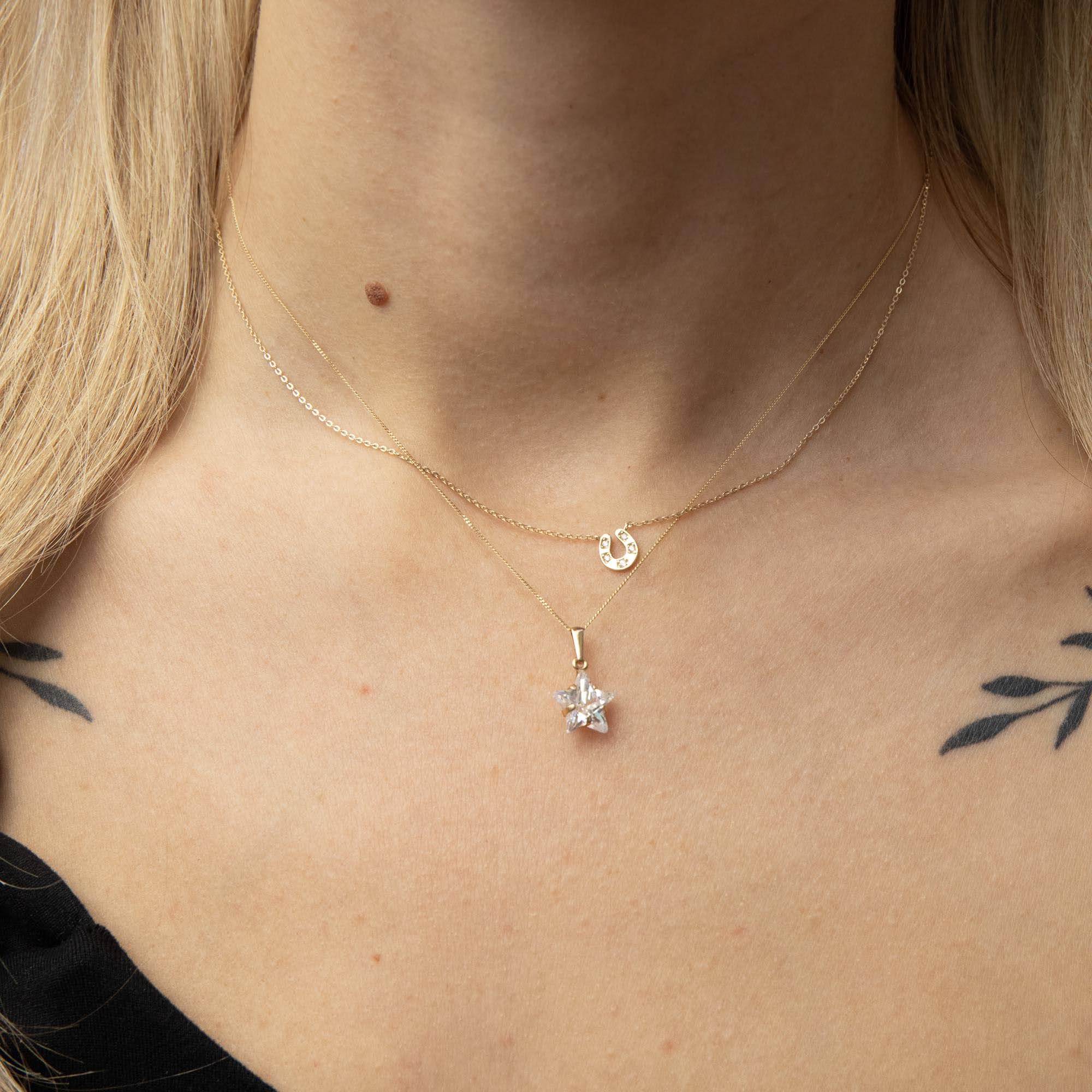 Close-up of a person wearing a gold necklace with a star-shaped pendant and horsehose necklace - seolgold