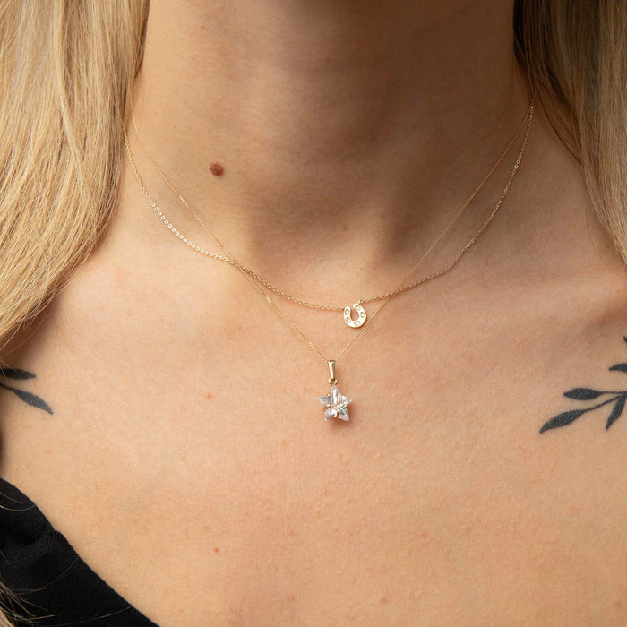 Close-up of a person wearing a gold necklace with a star-shaped pendant and horsehose necklace - seolgold