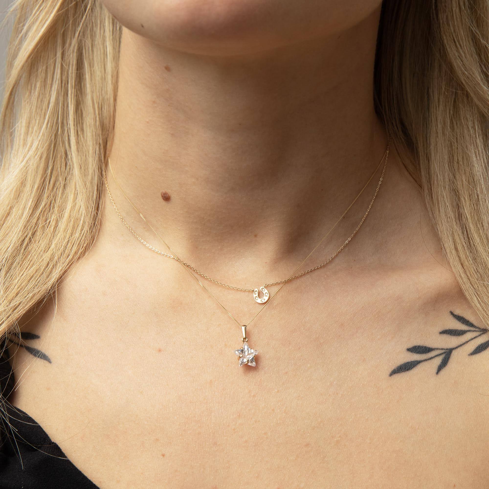 Close-up of a person wearing two gold necklaces with pendants - seolgold