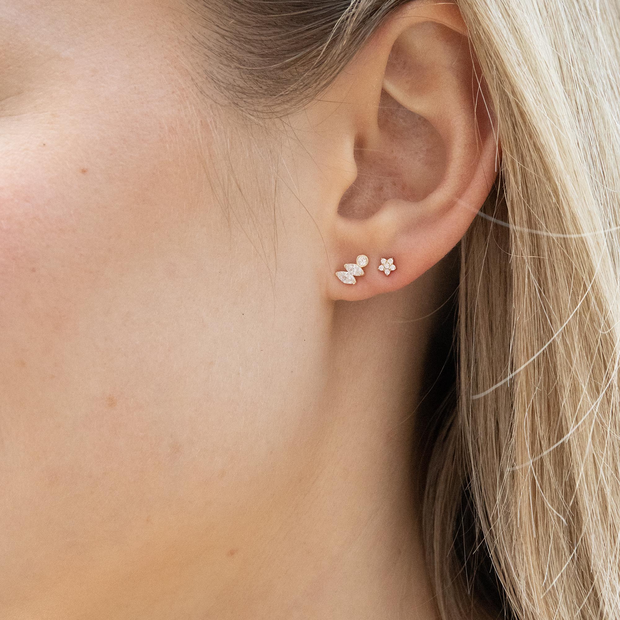 Close-up of an ear wearing a small earring with a blurred background - 9ct Solid Gold Pave CZ Star Studs - seolgold