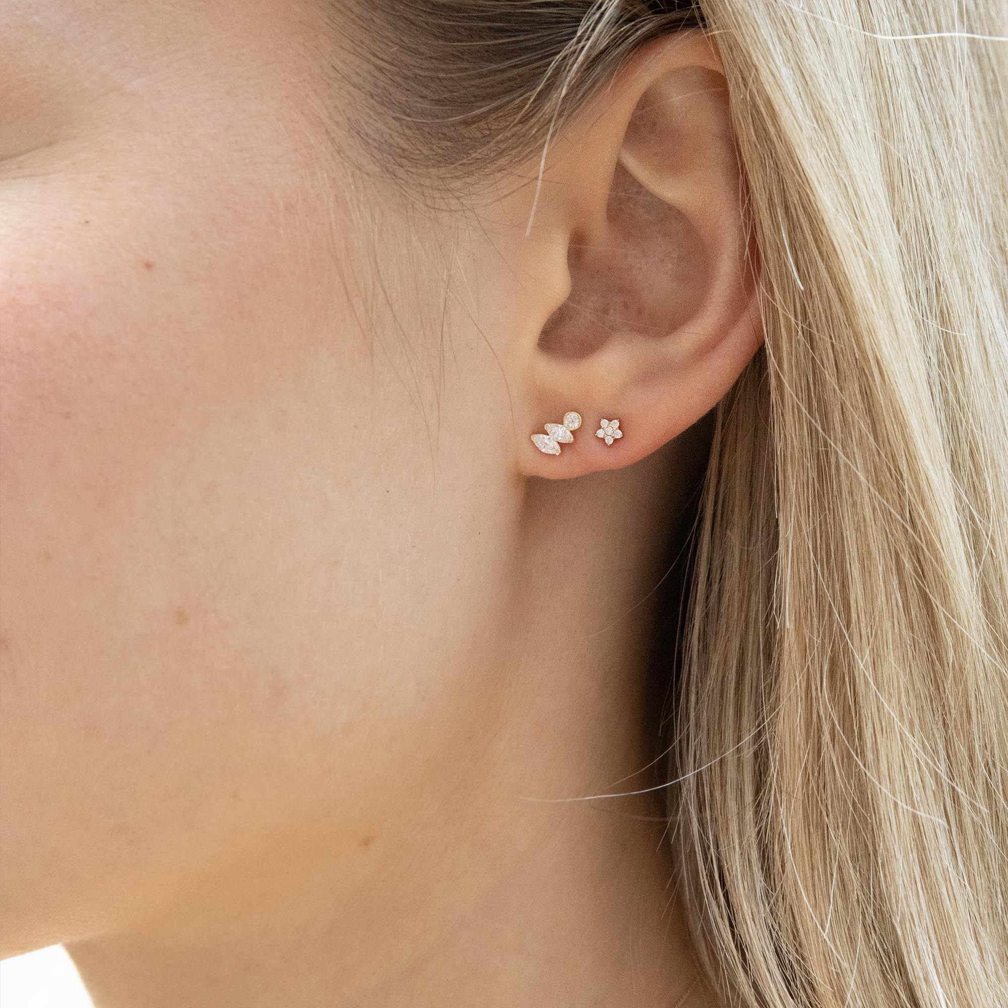 Close-up of an ear wearing a delicate earring with a blurred background - seolgold