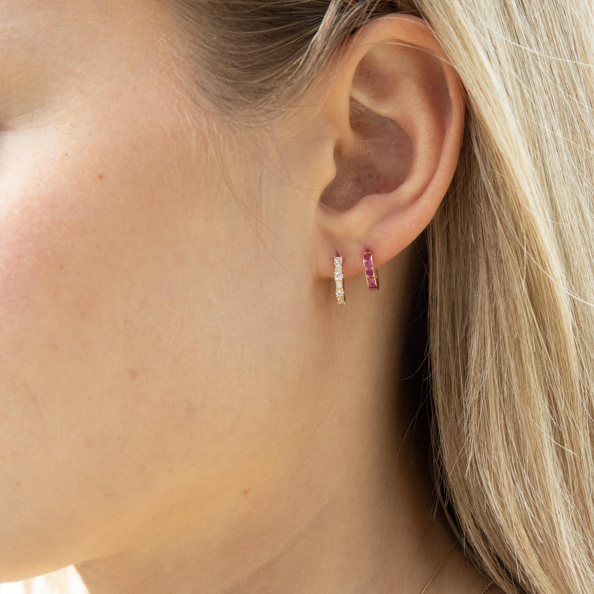 Close-up of an ear wearing two hoop earrings with a blurred background - solid gold hoop earrings - seolgold