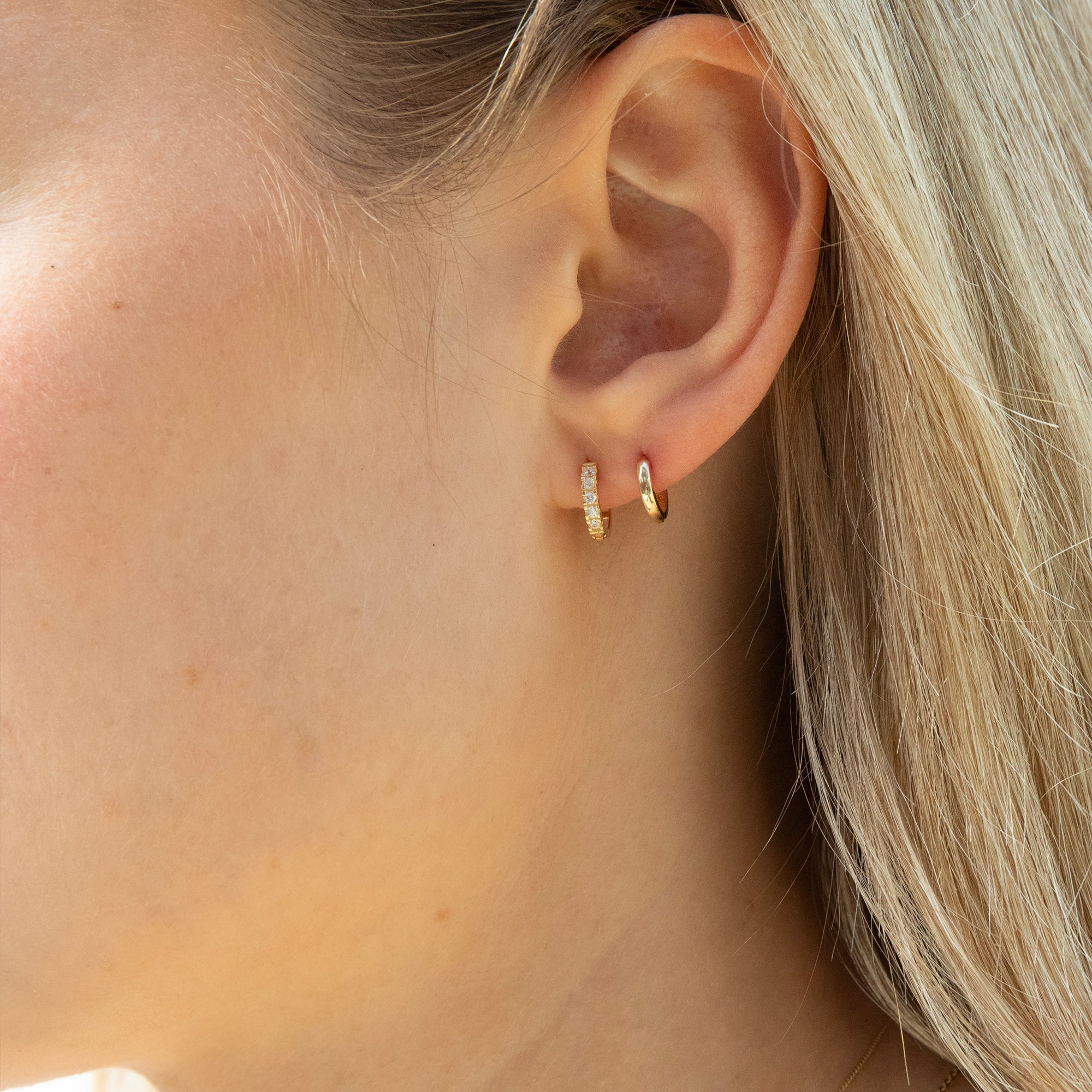 Close-up of an ear wearing gold hoop earrings with blonde hair - seolgold