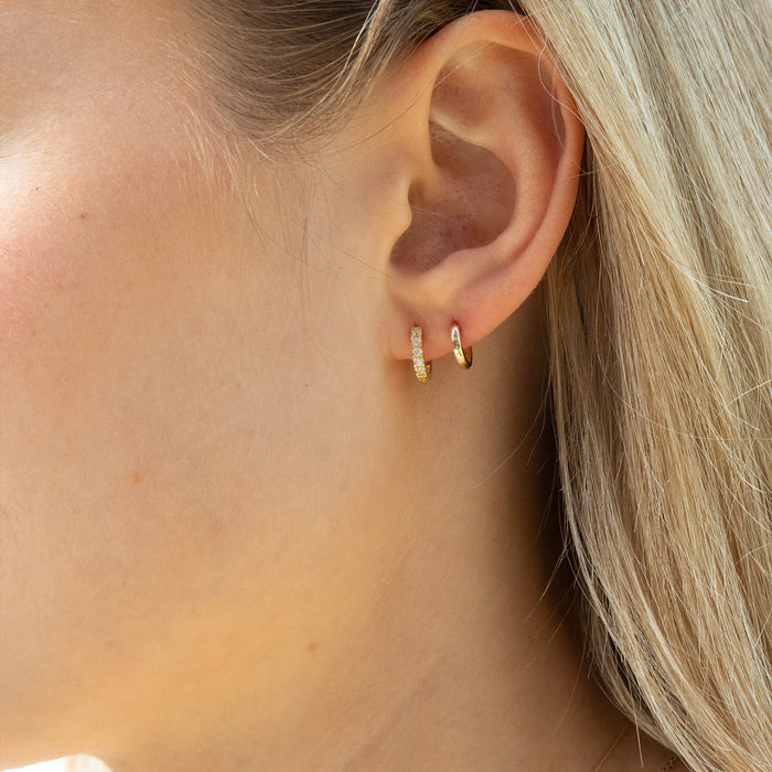 Close-up of an ear wearing gold hoop earrings with blonde hair - seolgold