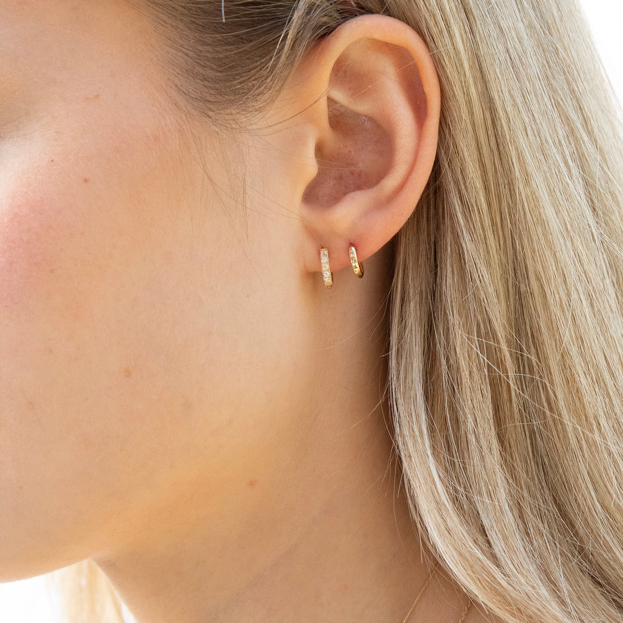 Close-up of a person wearing gold hoop earrings with light blonde hair - seolgold