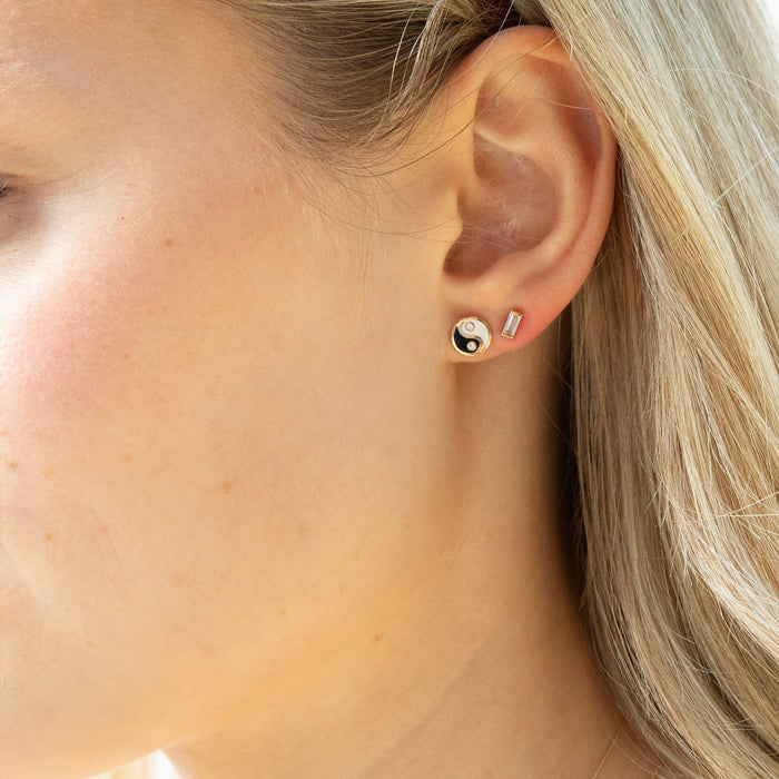 Close-up of an ear wearing a small earring with a yin yang design - seolgold