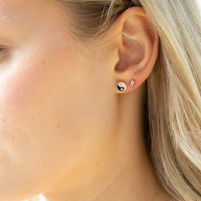 Close-up of an ear wearing a small earring with a yin yang design - seolgold